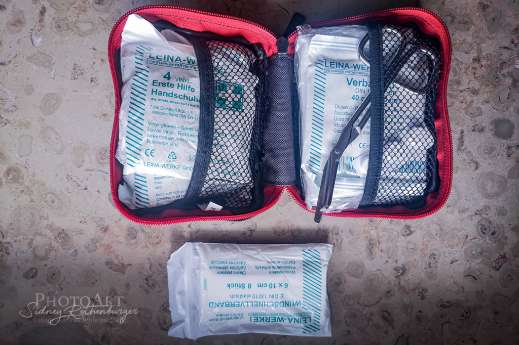 Geöffnetes Erste Hilfe-Kit mit danebenliegender Tüte gefüllt mit Pflastern